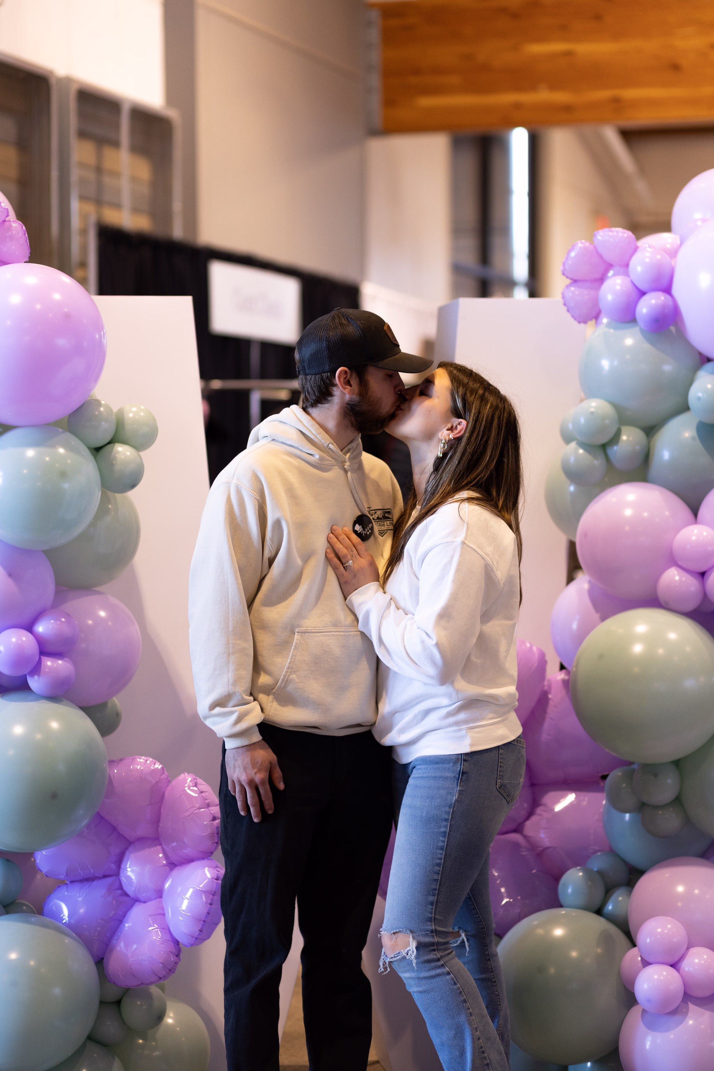 balloon decor salem wedding show - October 2026 Couple kissing surrounded by purple and sage balloon installations at Salem wedding show