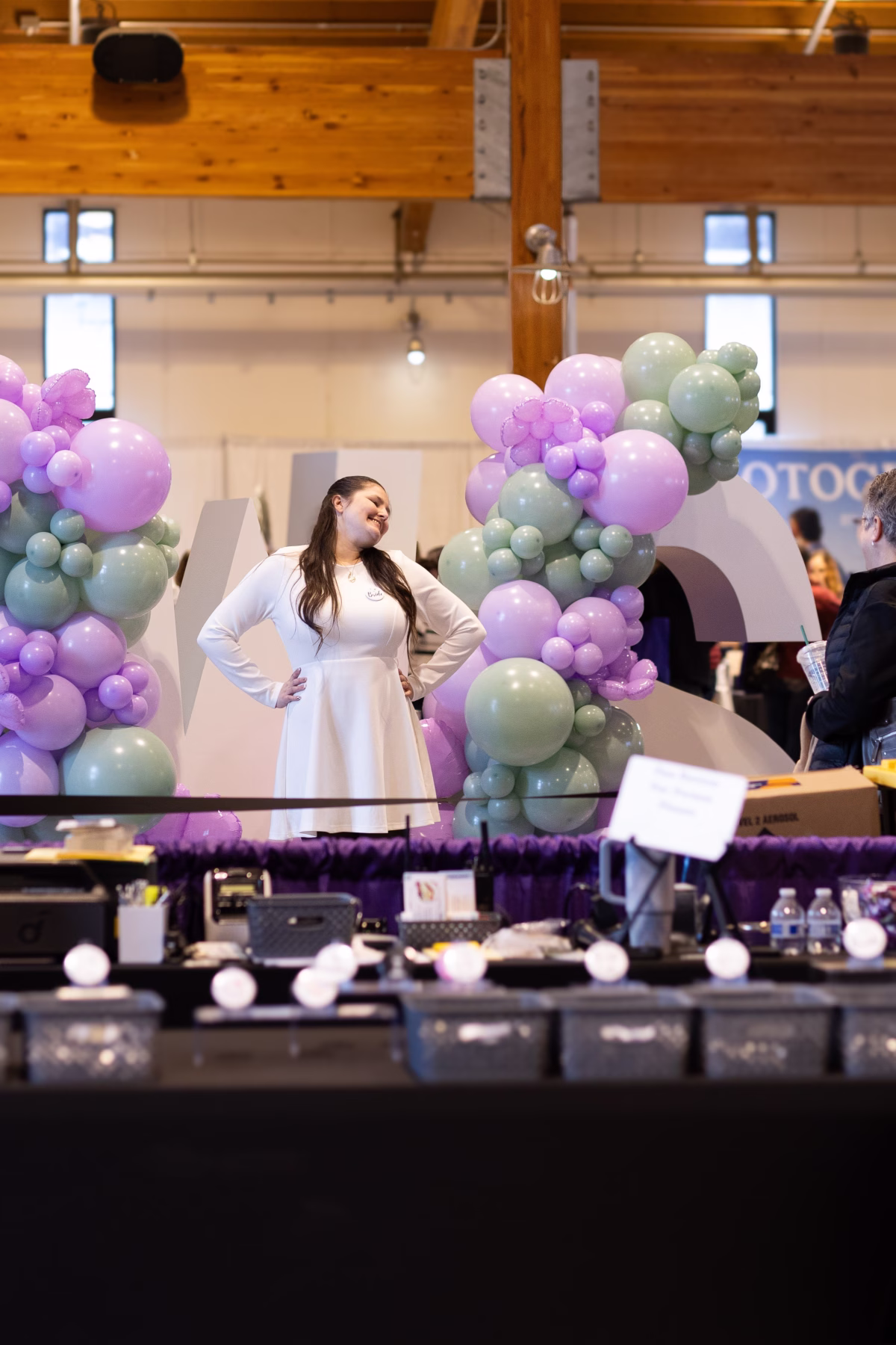 salem wedding show bridal expo balloon display venue - October 2026 Bride posing with purple and sage green balloon arch display at Salem Wedding Show bridal expo in Oregon venue