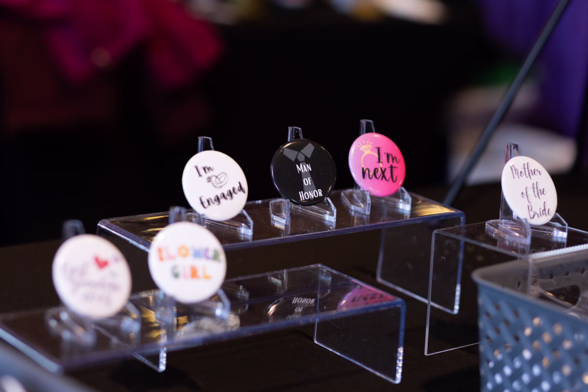 wedding role badges salem wedding show - October 2026 Wedding party role identification badges including engaged, man of honor, I'm next, and mother of bride displayed on clear acrylic stands at the Salem Wedding Show